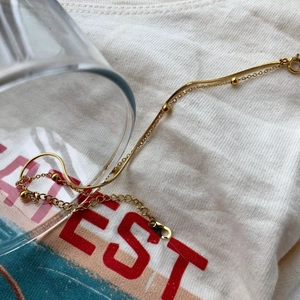 Détail d'un bracelet double couche doré avec petites perles et fermoir mousqueton