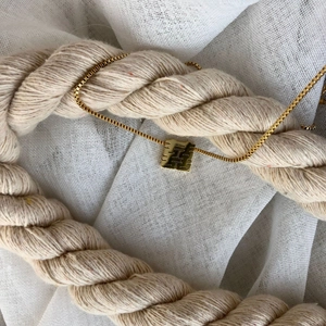 Macro detail of golden box chain and hollow rectangular Double Happiness pendant