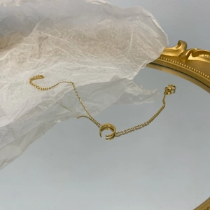 Collana a mezzaluna in acciaio al titanio placcato oro 18K con riflesso su specchio