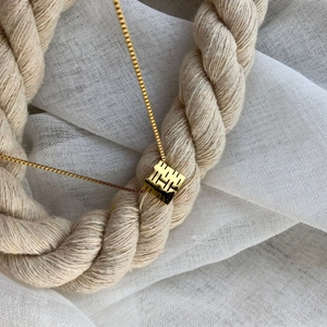 Classic Chinese double happiness gold necklace with hollow square pendant on linen background