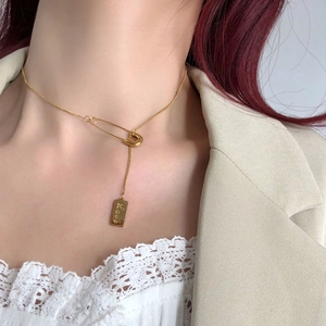 Minimalist gold pin necklace with engraved Love rectangular pendant worn by a model