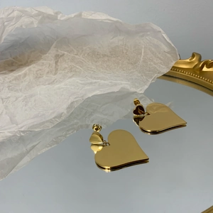 Elegant gold double heart dangle earrings displayed on a mirror for a modern look