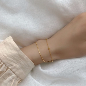 Vue détaillée d'un bracelet double couche doré avec chaîne serpent et accents perlés