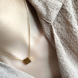 Detail of a gold square hollow Xi pendant on a box chain for a modern Chinese style look