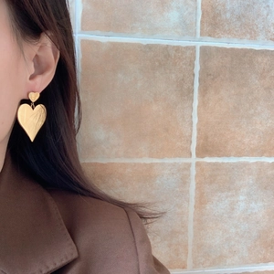 Golden double heart drop earrings worn by a model in a minimalist geometric style