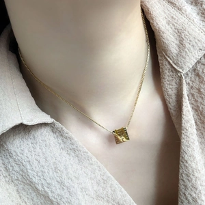 Macro view of gold square pendant with double happiness character on box chain