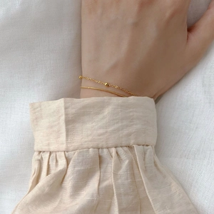 Gros plan d'un bracelet doré double épaisseur avec chaîne serpent et petites perles