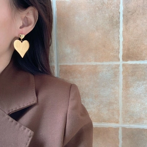 Close-up of double layered heart-shaped drop earrings in polished gold finish