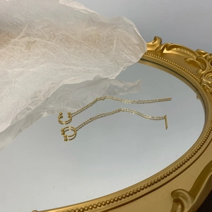 Detailed view of long gold tassel earrings with ear bone clip and thin chain link