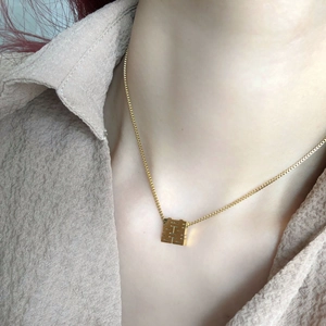 Close-up of golden Chinese Double Happiness pendant on box chain necklace
