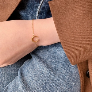 Primo piano di un braccialetto minimalista a mezzaluna d'oro indossato sul polso