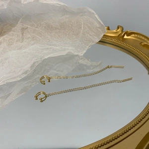 Minimalist gold long tassel ear cuffs with thin cross chains on a vintage mirror