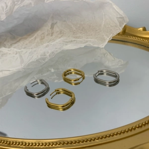 Macro view of geometric square hoop earrings in gold and silver finish on a mirror