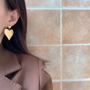 Detail of gold double heart earrings on model showing polished finish and drop design