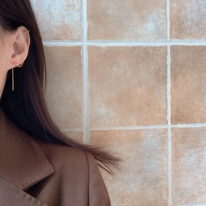 Minimalist gold tassel chain earrings with integrated ear cuff design on model