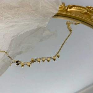 Collana a dischi dorati minimalista su superficie a specchio con riflesso elegante