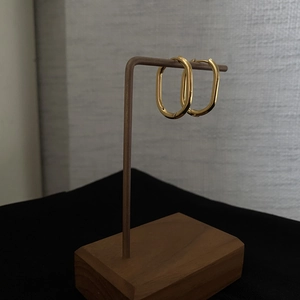 Vintage gold oval geometric hoop earrings displayed on a minimalist wooden T-stand