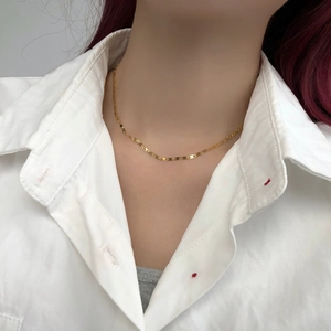 Primo piano di una collana a maglia piatta dorata minimalista su una modella