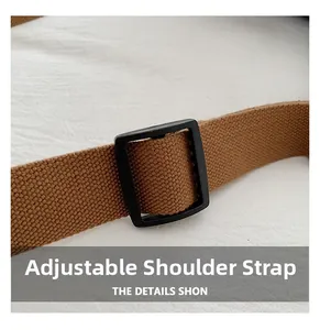 Gros plan sur la bandoulière réglable en toile marron avec boucle noire du sac
