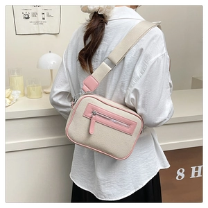 Dettaglio della borsa a tracolla in tela beige con finiture in pelle rosa e tracolla regolabile