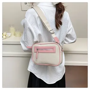 Dettaglio di una borsa a tracolla in tela crema con finiture in pelle rosa su modella