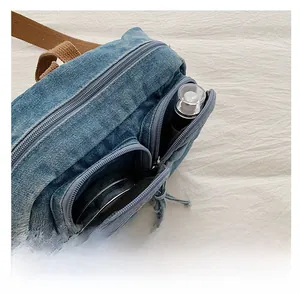 Détails des poches avant du sac bandoulière en jean montrant le rangement du maquillage