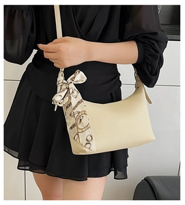 Detail of cream leather shoulder bag with decorative vintage silk scarf and gold lettering
