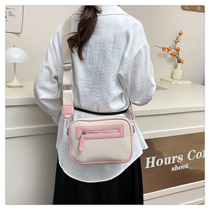 Dettaglio della borsa a tracolla in tela beige con finiture in pelle rosa indossata