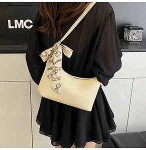 Detail of cream leather hobo bag featuring a decorative logo silk scarf on the strap