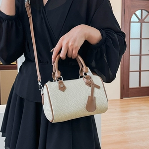 Mini bicolor Boston bag in cream and brown leather worn by a model in black dress
