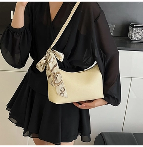 Detail of cream crescent underarm bag with elegant silk scarf on shoulder strap