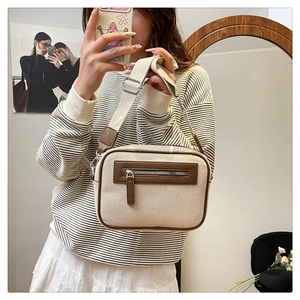 Dettaglio della borsa quadrata in tela beige con finiture in pelle marrone e tracolla