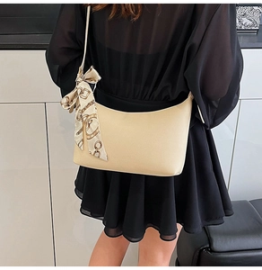 Detail of beige crescent underarm bag with decorative silk scarf on a model back view