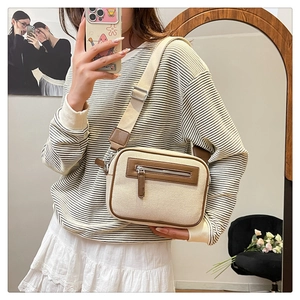 Dettaglio della borsa a tracolla in tela con finiture in pelle marrone indossata con stile