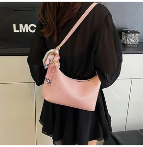 Detail of pink hobo bag with a decorative silk scarf, styled as a shoulder bag