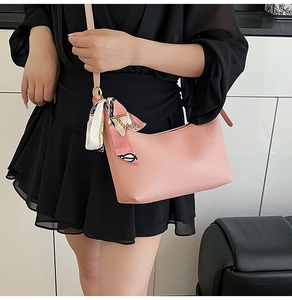 Detail of light pink hobo bag with a decorative chain pattern silk scarf on the strap