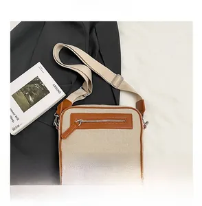 Dettaglio della piccola borsa a tracolla quadrata in tela beige e finiture in pelle marrone
