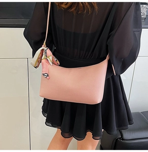 Pink faux leather shoulder bag with decorative floral scarf accessory on black outfit