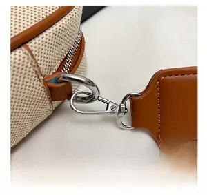 Dettaglio del gancio in metallo argento su borsa in tela beige e pelle marrone