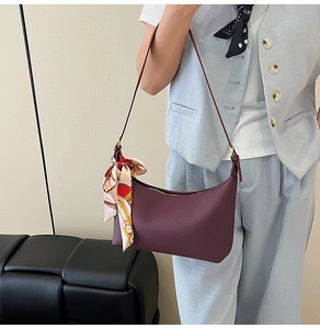Detail of burgundy crescent shoulder bag featuring a colorful silk scarf on the side