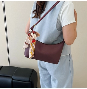 Close-up of burgundy hobo bag with colorful silk scarf and gold metal buckle detail