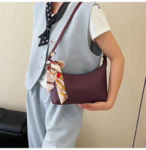 Close-up of burgundy underarm bag with lychee texture leather and a decorative silk scarf