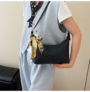 Close-up of black crescent shoulder bag with silk scarf detail on female model