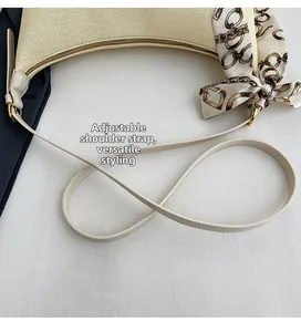 Detail of beige canvas hobo bag with adjustable leather strap and silk scarf accessory