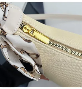 Detail of beige lychee texture leather bag with smooth gold zipper and printed silk scarf