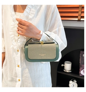 Detailed view of luxury dark green square handbag with gold push lock and textured flap