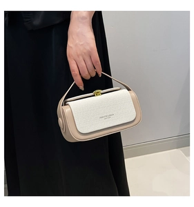 Detail of elegant two-tone handbag with woven texture and vintage gold metal clasp