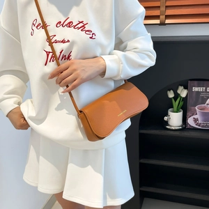 Chic caramel brown pebbled leather shoulder bag shown on a model in a minimal interior