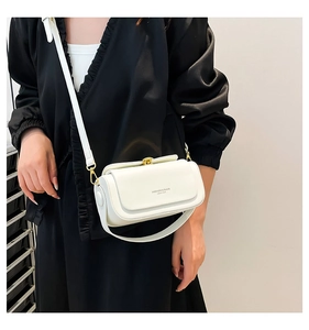 Detail of white leather mini crossbody bag featuring a gold twist lock and adjustable strap