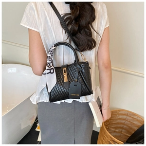 Detail of black woven texture handbag with polka dot scarf and golden metal lock